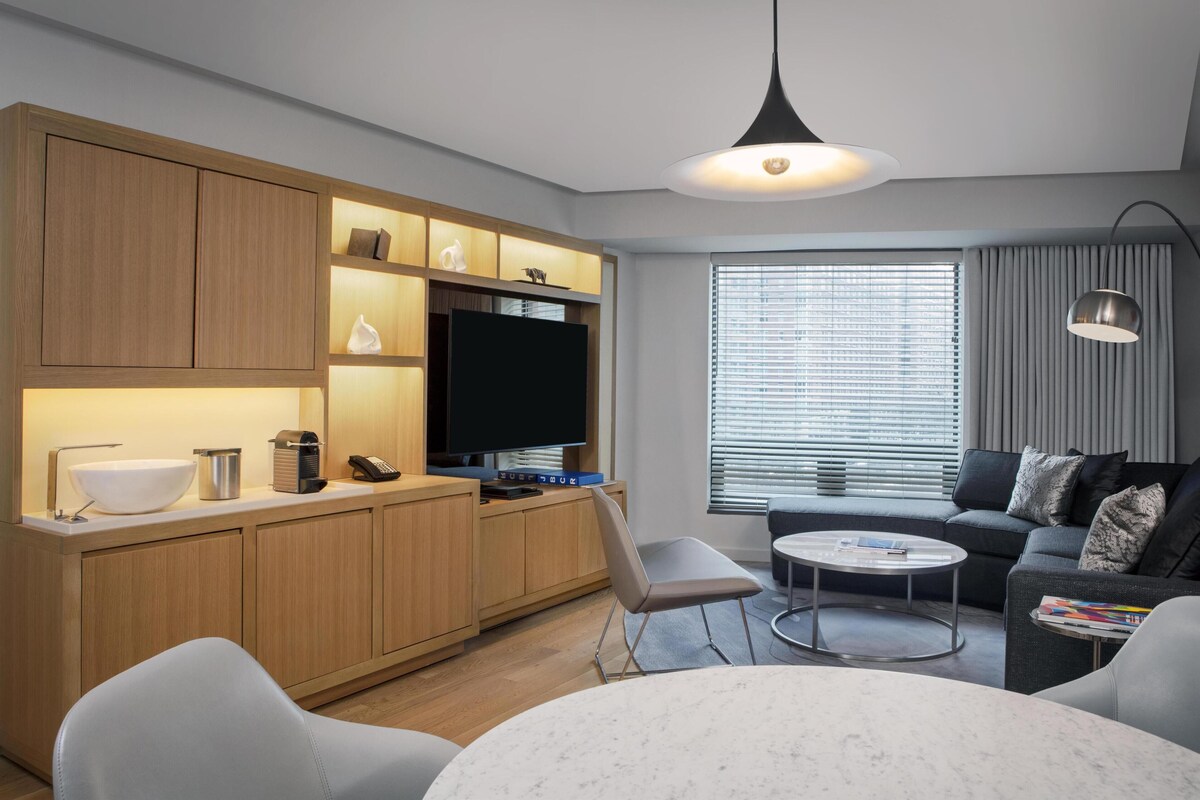 A modern kitchen with wooden cabinets, a built-in TV, and a dining area with a round table and chairs.