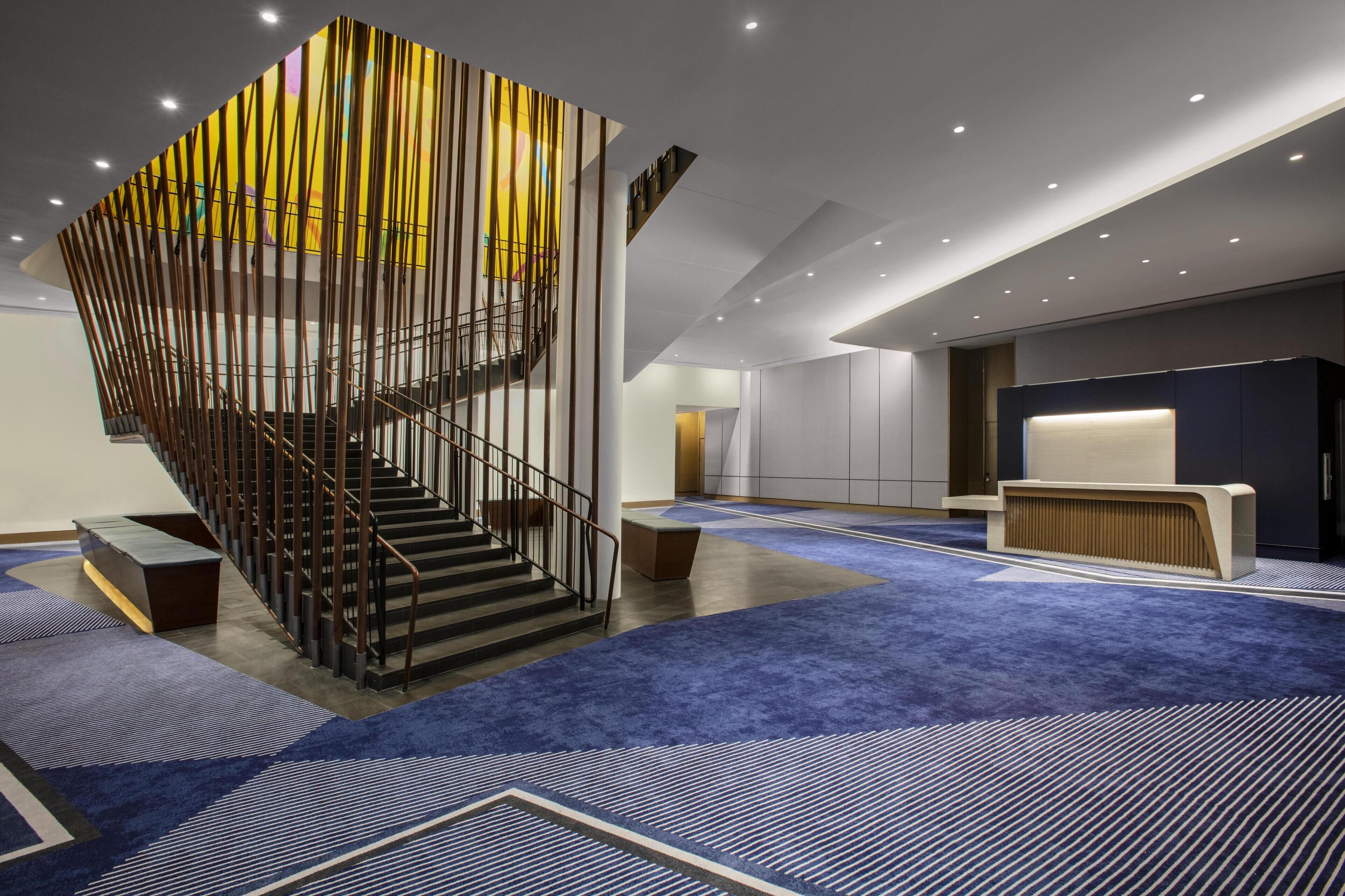 A modern interior with a spiral staircase, a reception desk, and a blue carpeted floor.