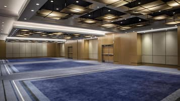 A spacious room with a blue carpet, recessed lighting, and a modern ceiling design.