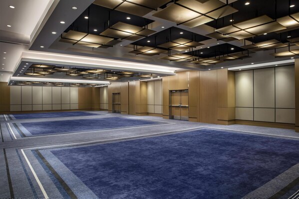 A spacious room with a blue carpet, recessed lighting, and a modern ceiling design. - Conrad New York Downtown (New York)