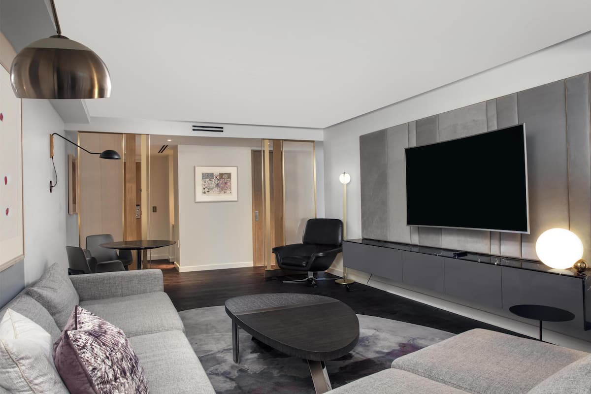 A modern living room with a sofa, coffee table, TV, and a dining area with chairs and a table.