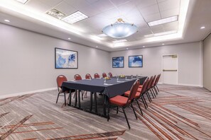 A conference room with a long table, chairs, and artwork on the walls.