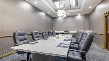 A conference room with a long table, multiple chairs, and a ceiling light fixture.