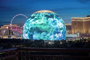 Une grande sphère illuminée à la texture nuageuse, une grande roue et, au loin, l’hôtel vénitien.