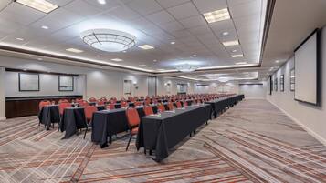 A conference room with long tables, chairs, and a carpeted floor.