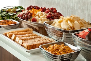 En buffet med et udvalg af mad, herunder frugt, oste, kiks og nødder.