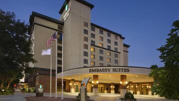 A hotel with a prominent sign reading 'EMBASSY SUITES' and a flagpole with the American flag.