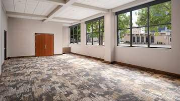 A spacious room with large windows, a door, and patterned carpet.