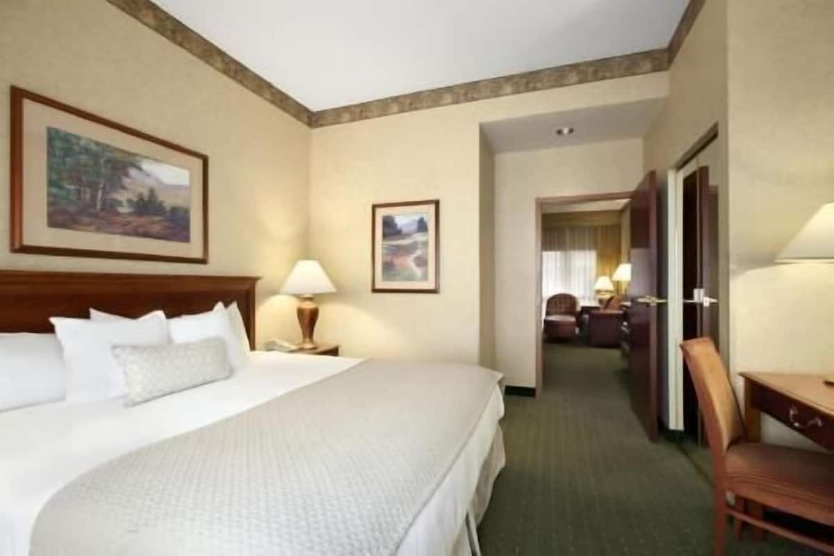 A hotel room with a large bed, a desk, and a chair.
