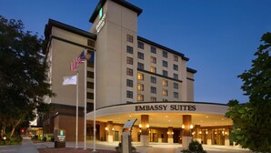 L'esterno dell'hotel Embassy Suites con un ingresso curvo, diversi piani e un'asta con la bandiera americana.
