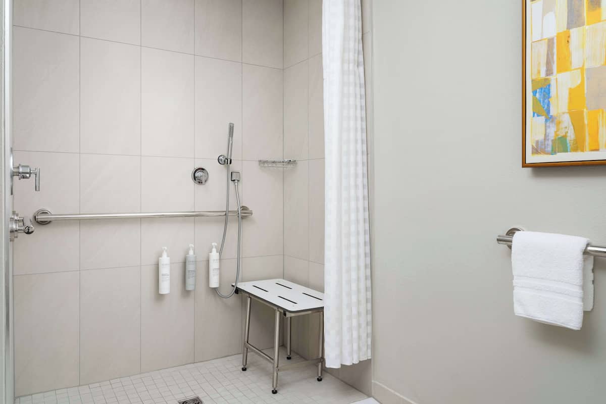 A shower area with a grab bar, a small step stool, and a towel rack.