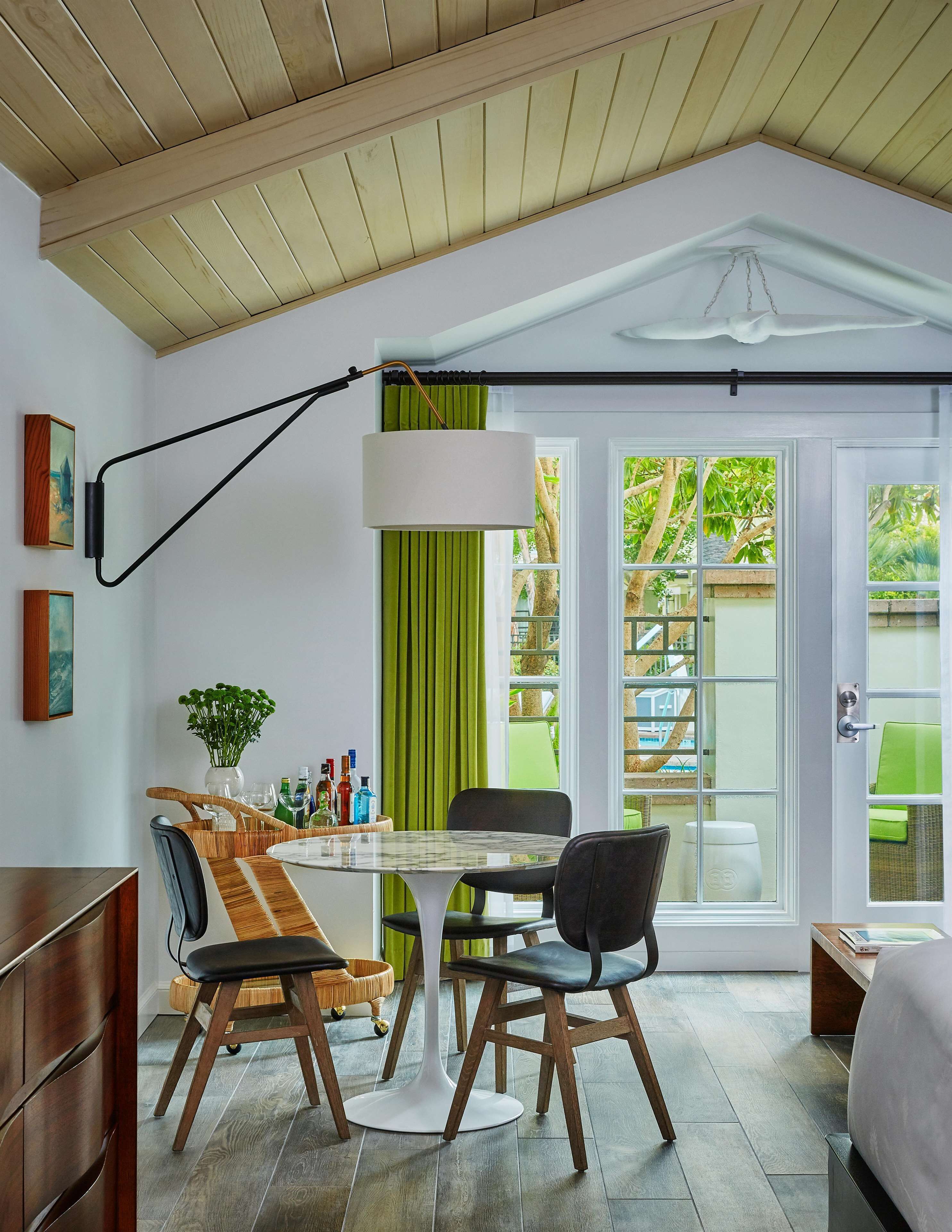 Habitación moderna con una mesa de comedor, sillas, una lámpara de pie y vistas a través de una puerta corrediza de vidrio.