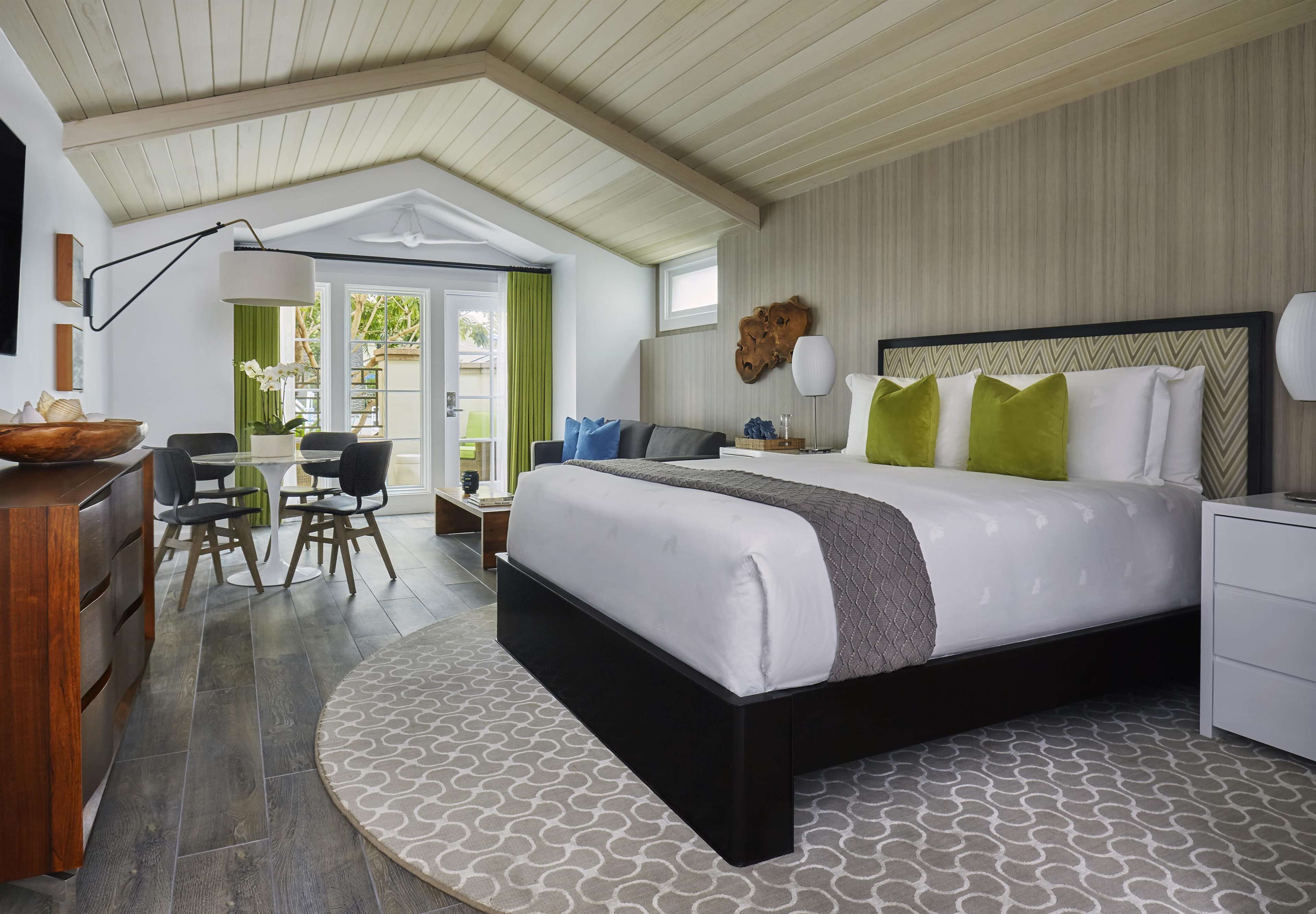 A modern bedroom with a large bed, a desk, and a dining area.
