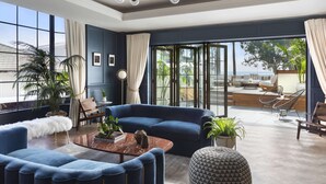 A modern living room with a blue sofa, a round coffee table, and a view of the outdoors.