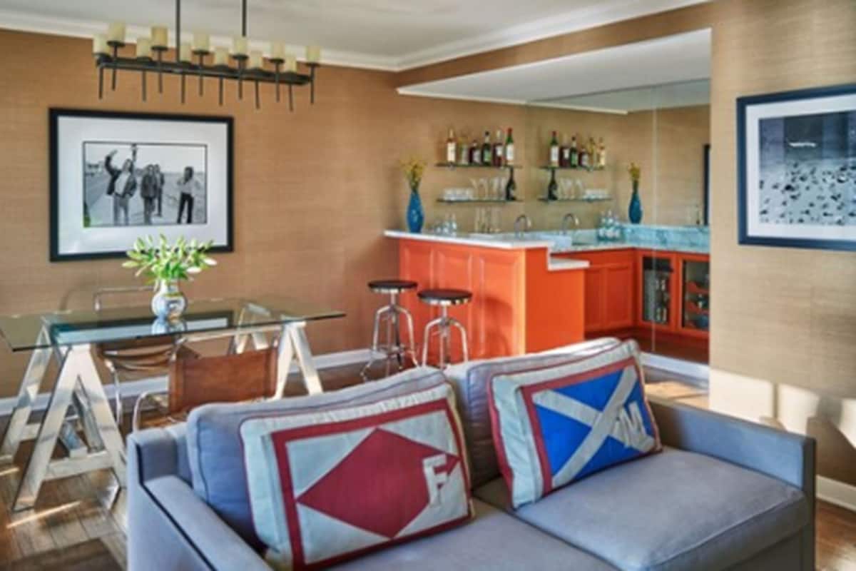 A modern living room with a sofa, a glass coffee table, and a dining area with a bar.