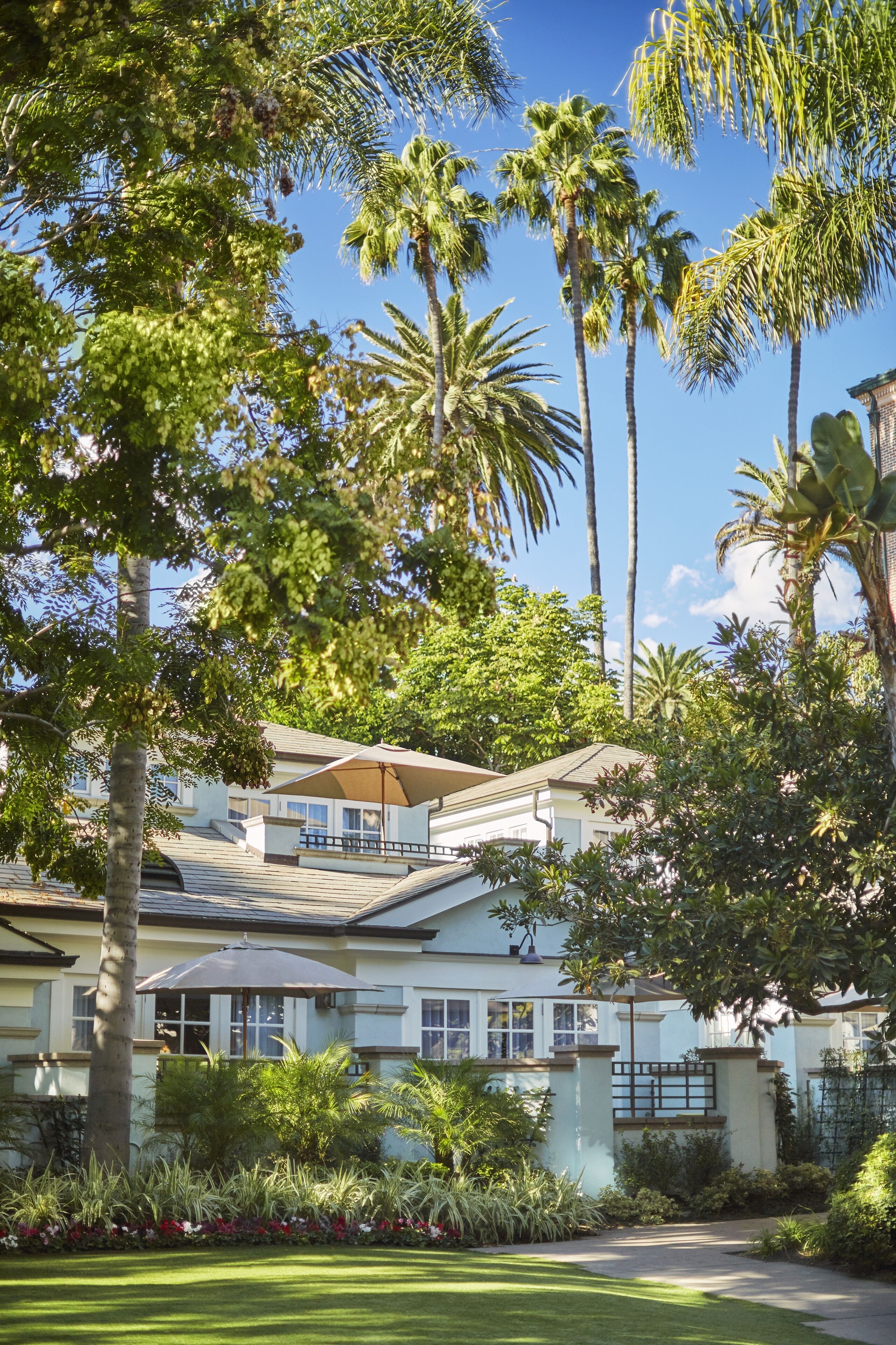 A two-story building with a covered patio area, surrounded by lush greenery and palm trees.