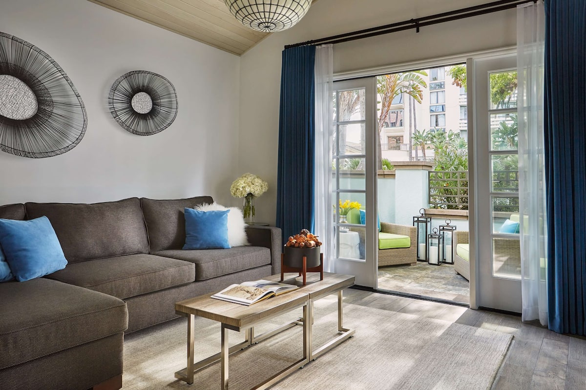 A modern living room with a sectional sofa, a wooden coffee table, and a view of the outdoor patio through large sliding glass doors.