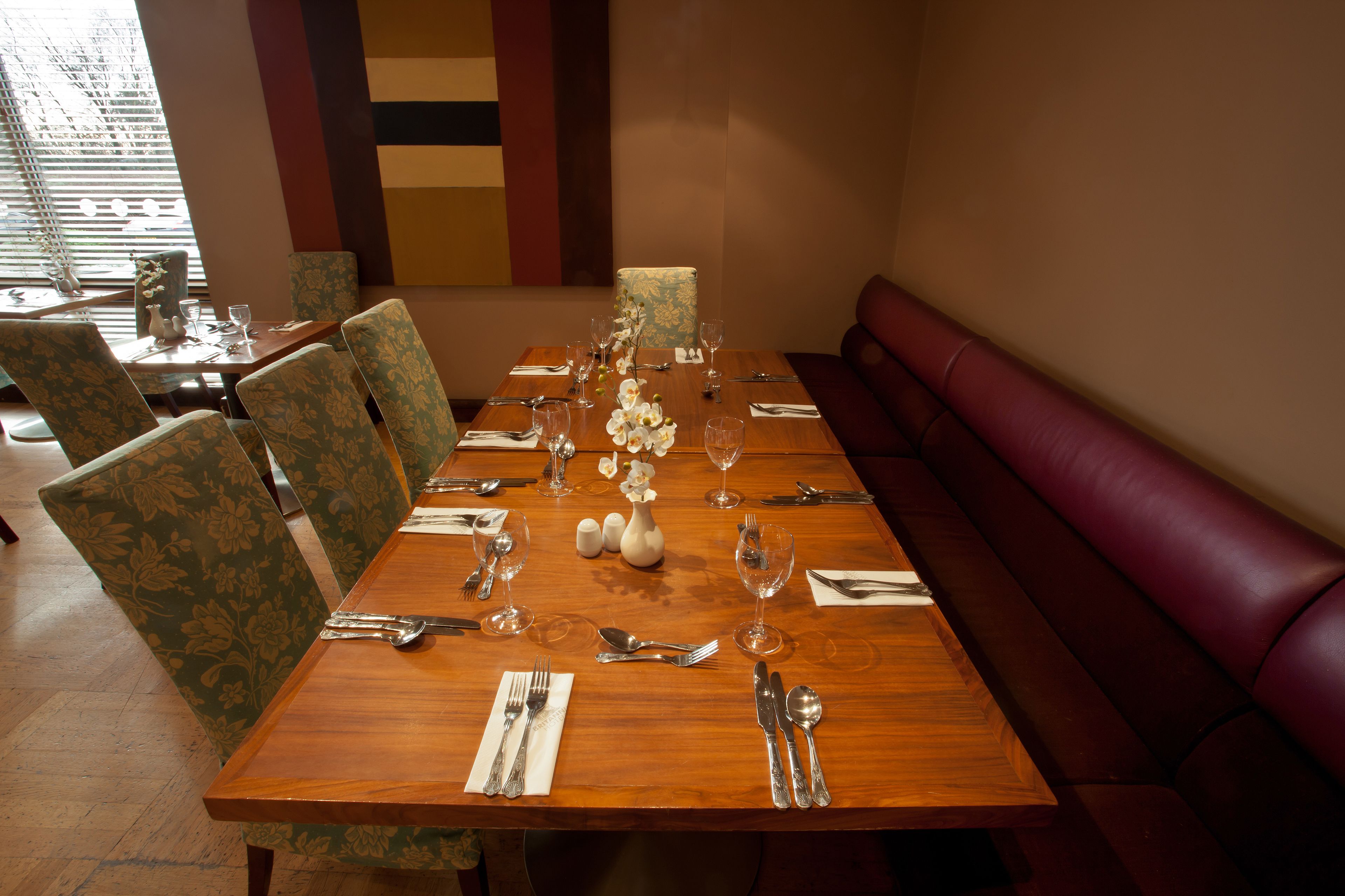 A dining table set with chairs, a vase of flowers, and a bench.