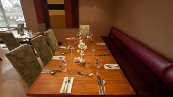 A dining table set with chairs, a vase of flowers, and a bench.
