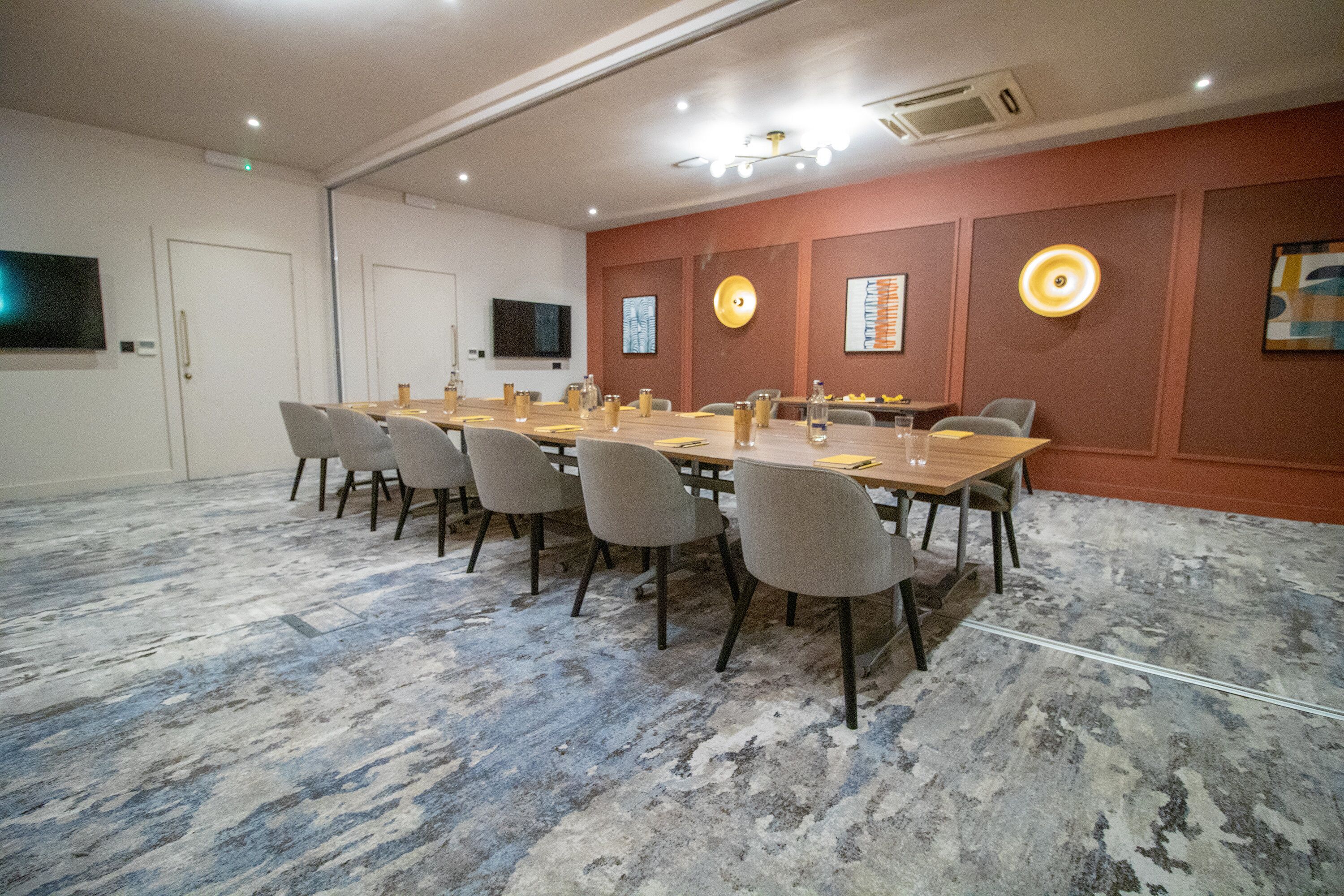 A conference room with a long table, chairs, a flat-screen TV, and wall-mounted decor.