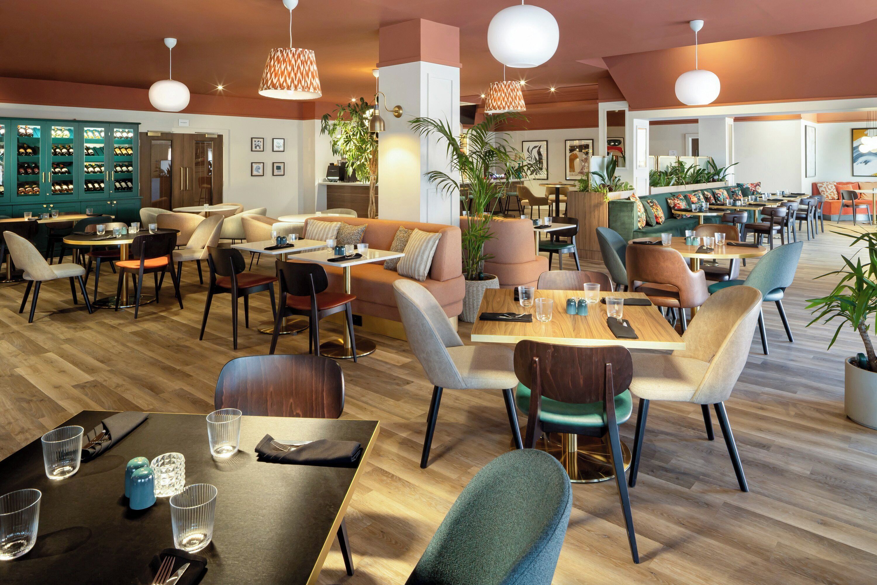 A restaurant with multiple dining areas, tables, chairs, and a bar area with a wine display.