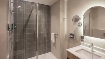A modern bathroom with a glass-enclosed shower, a vanity with a sink, and a large mirror.