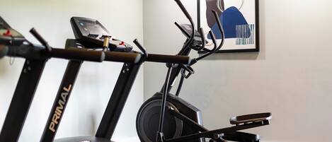 Un vélo d’appartement doté d’un écran numérique, un tableau abstrait accroché au mur et un tableau encadré.