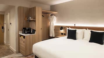 Una habitación de hotel con cama, mesitas de noche, un armario y una bata colgada en un perchero.