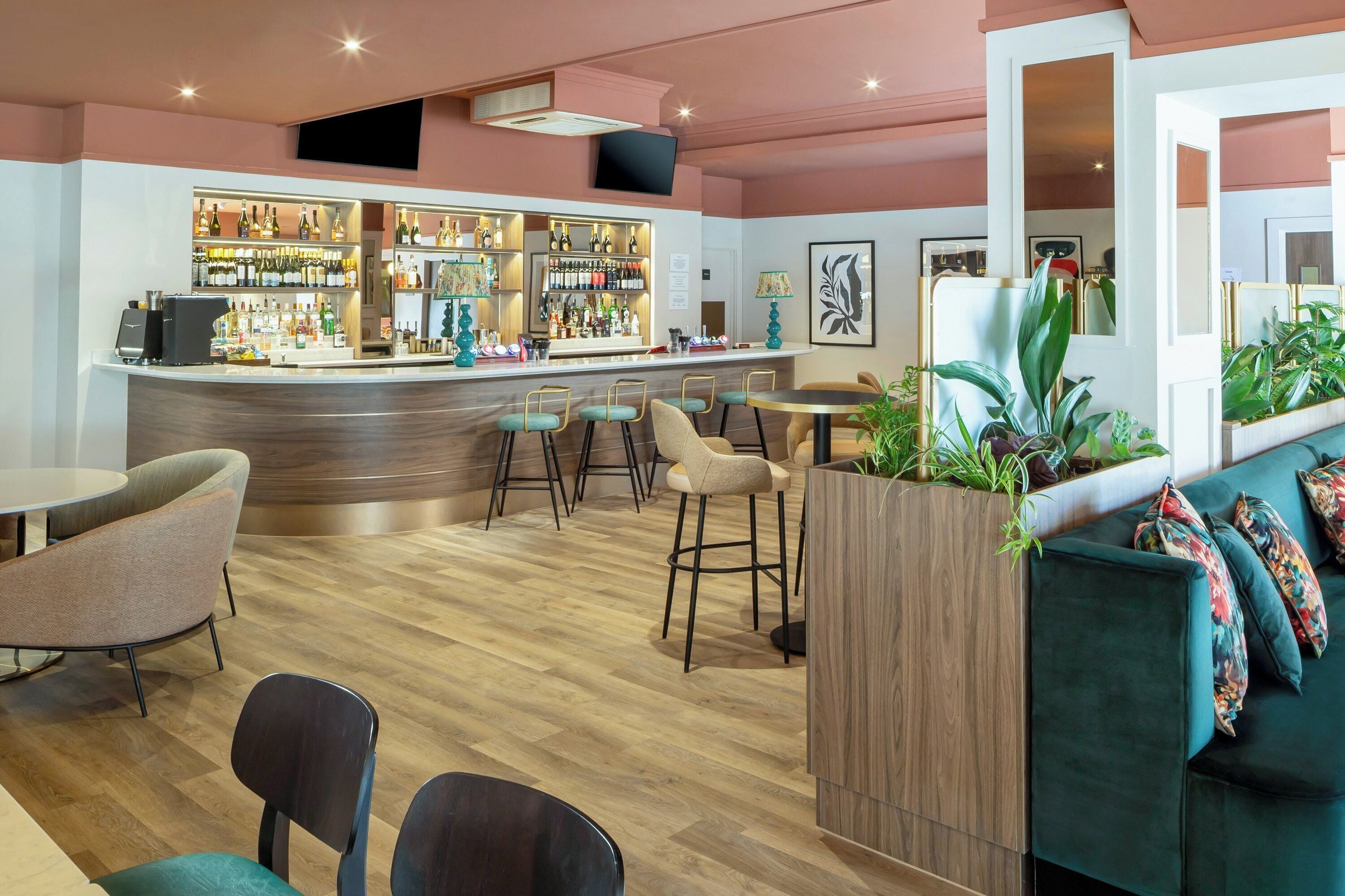 A bar area with a counter, stools, and a seating area with a sofa and chairs.