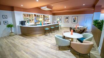 A bar area with a counter, bar stools, and a seating area with round tables and chairs.