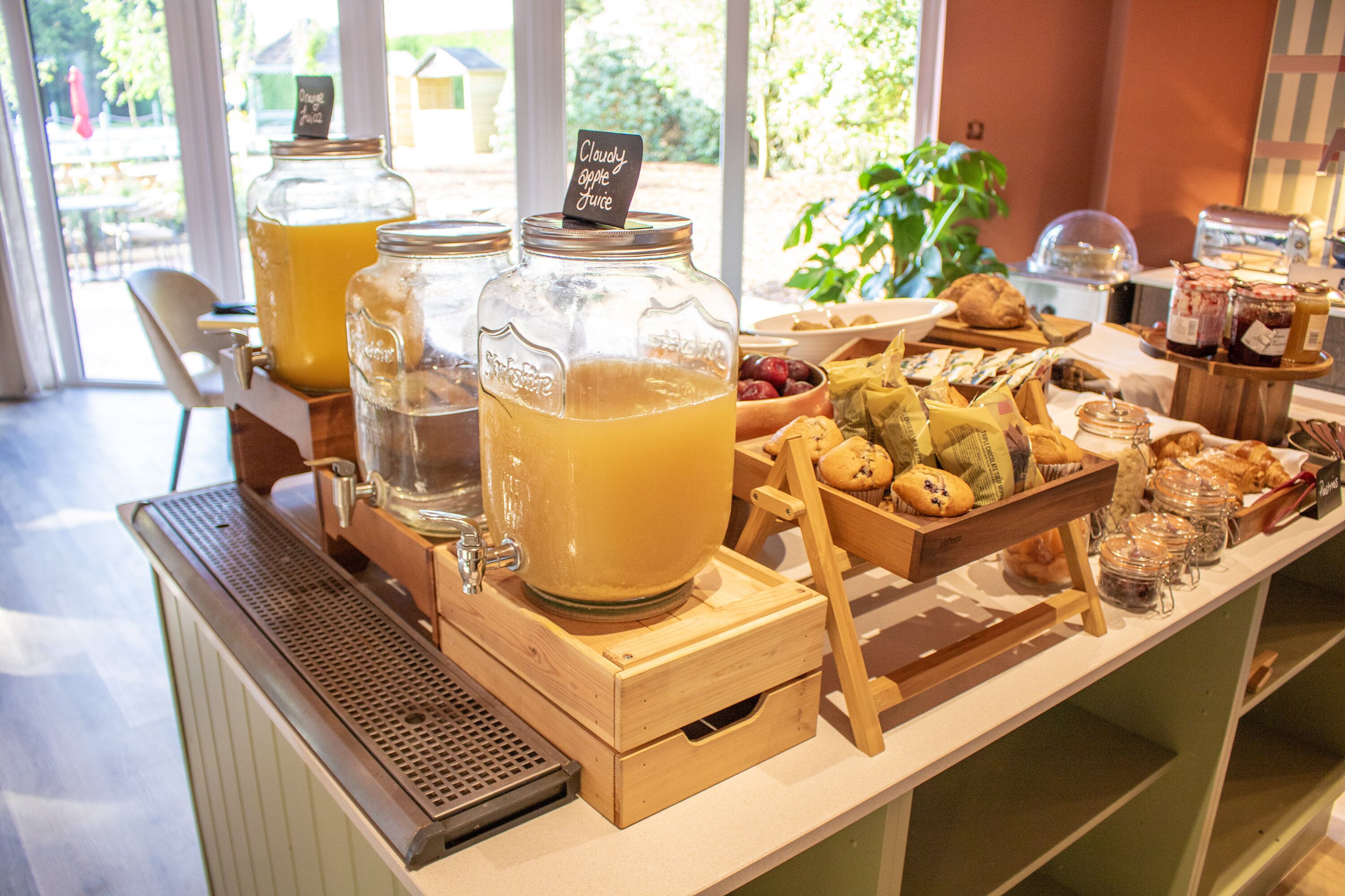 A breakfast buffet with various food items and a juice station.