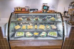 Vitrina de panadería con diversos productos horneados y sándwiches.