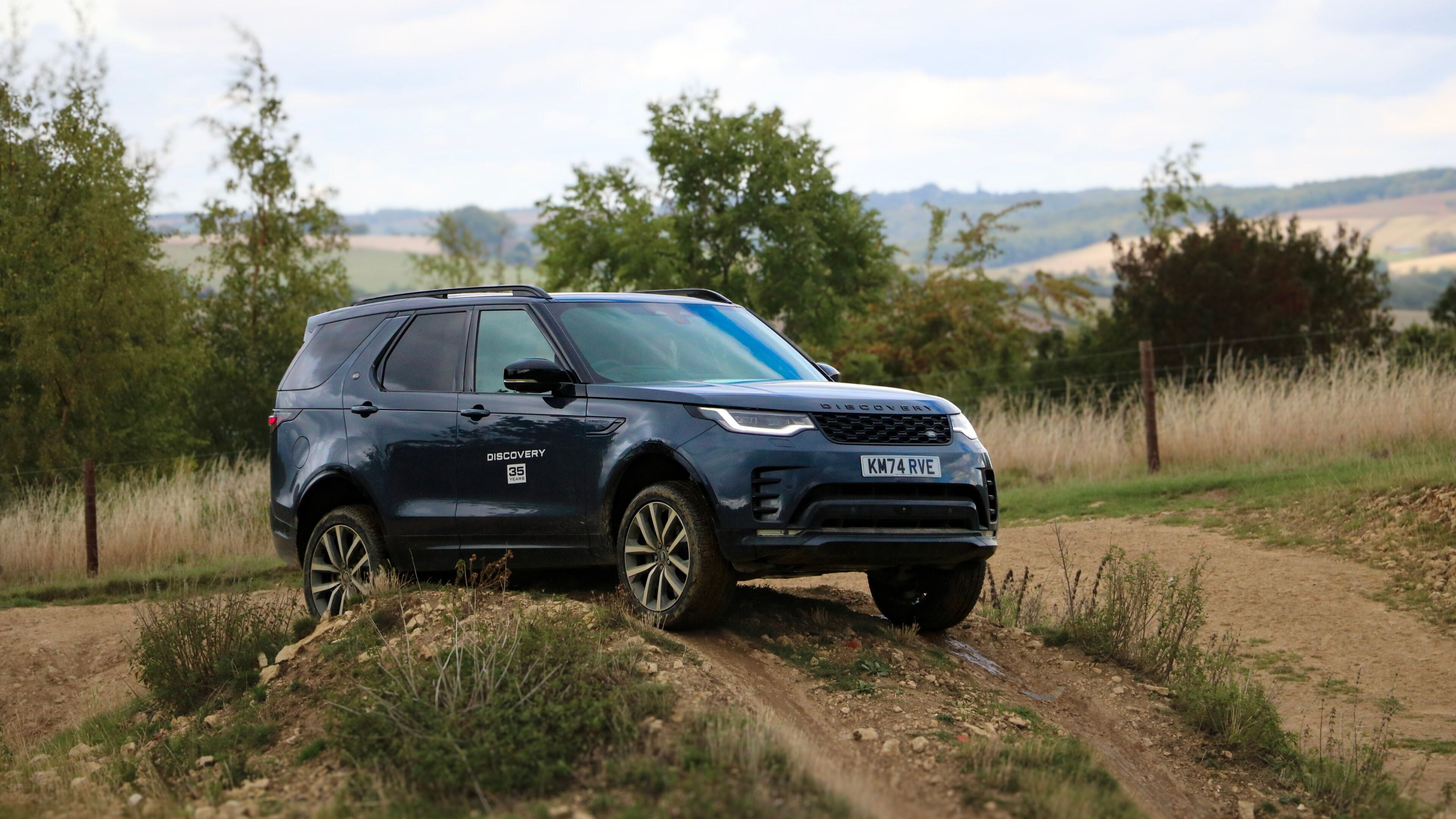 Un SUV azul oscuro sobre un camino de tierra en un entorno rural.