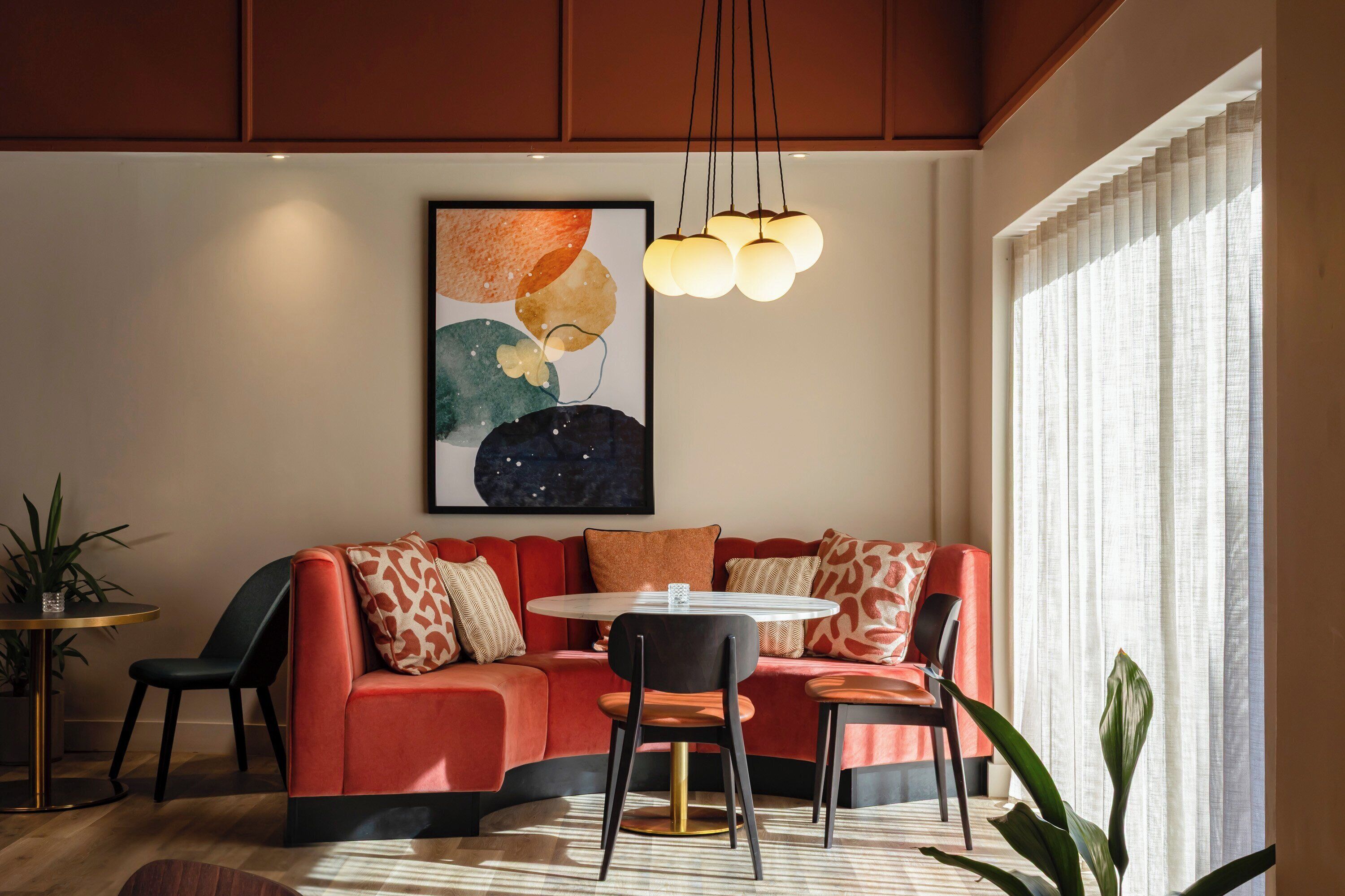 Una sala de estar moderna con un sofá rojo, una mesa de centro redonda y una lámpara colgante.