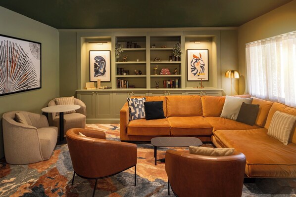 Una sala de estar con un sofá modular, sillones, una mesa de centro y una estantería decorada con objetos.