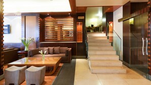 A modern hotel lobby with a staircase, seating area, and a reception desk. - Le Commodore (Beirut)