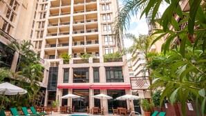 A hotel with a swimming pool, green lounge chairs, and a red awning. - Le Commodore (Beirut)