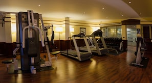 A gym with treadmills, weight machines, and a mirror wall.