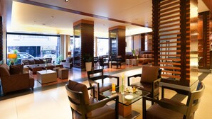 A spacious lobby with modern furniture, a glass coffee table, and a large window offering a view of the street. - Le Commodore (Beirut)
