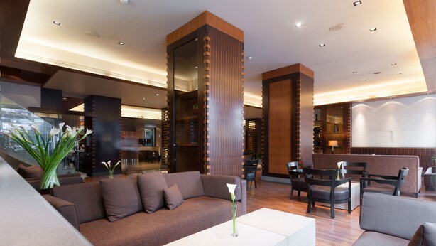 A modern lobby with a brown sofa, white coffee table, and wooden accents. - Le Commodore (Beirut)