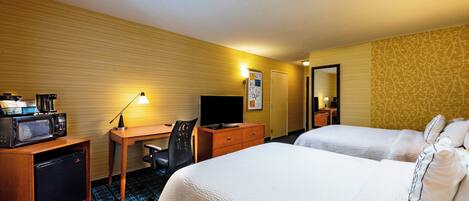 A hotel room with two beds, a desk with a computer, a TV, and a microwave.