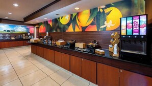 A hotel reception area with a long counter, a coffee machine, and a fruit juice dispenser. - Fairfield Inn by Marriott Battle Creek (Battle Creek)