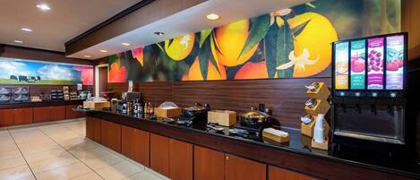 A hotel reception area with a long counter, a coffee machine, and a fruit juice dispenser.