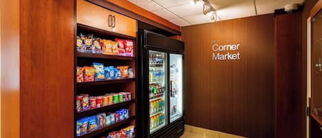 Un mercado de barrio con un mostrador refrigerado y estantes con snacks.