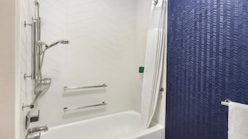 Ein modernes Badezimmer mit einer weißen Badewanne, einer Dusche inklusive Regendusche und einer blauen Wand mit Struktur.