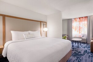 Una habitación de hotel con una cama grande, una mesita de noche, una pequeña mesa y una silla.
