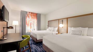 A hotel room with two beds, a desk, a chair, a television, and a window with curtains.