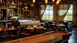 Un restaurante acogedor con mobiliario de madera, lámparas colgantes y una zona de bar.