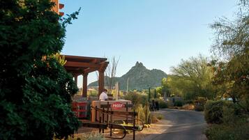 A desert-themed outdoor seating area with a 'PROOF' sign, cacti, and a mountain in the background.