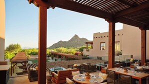 An outdoor patio with wooden furniture, a pool, and a mountain view. - Four Seasons Resort Scottsdale at Troon North (Scottsdale)